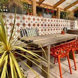 Covered terrace with colourful chairs and patterned tiles